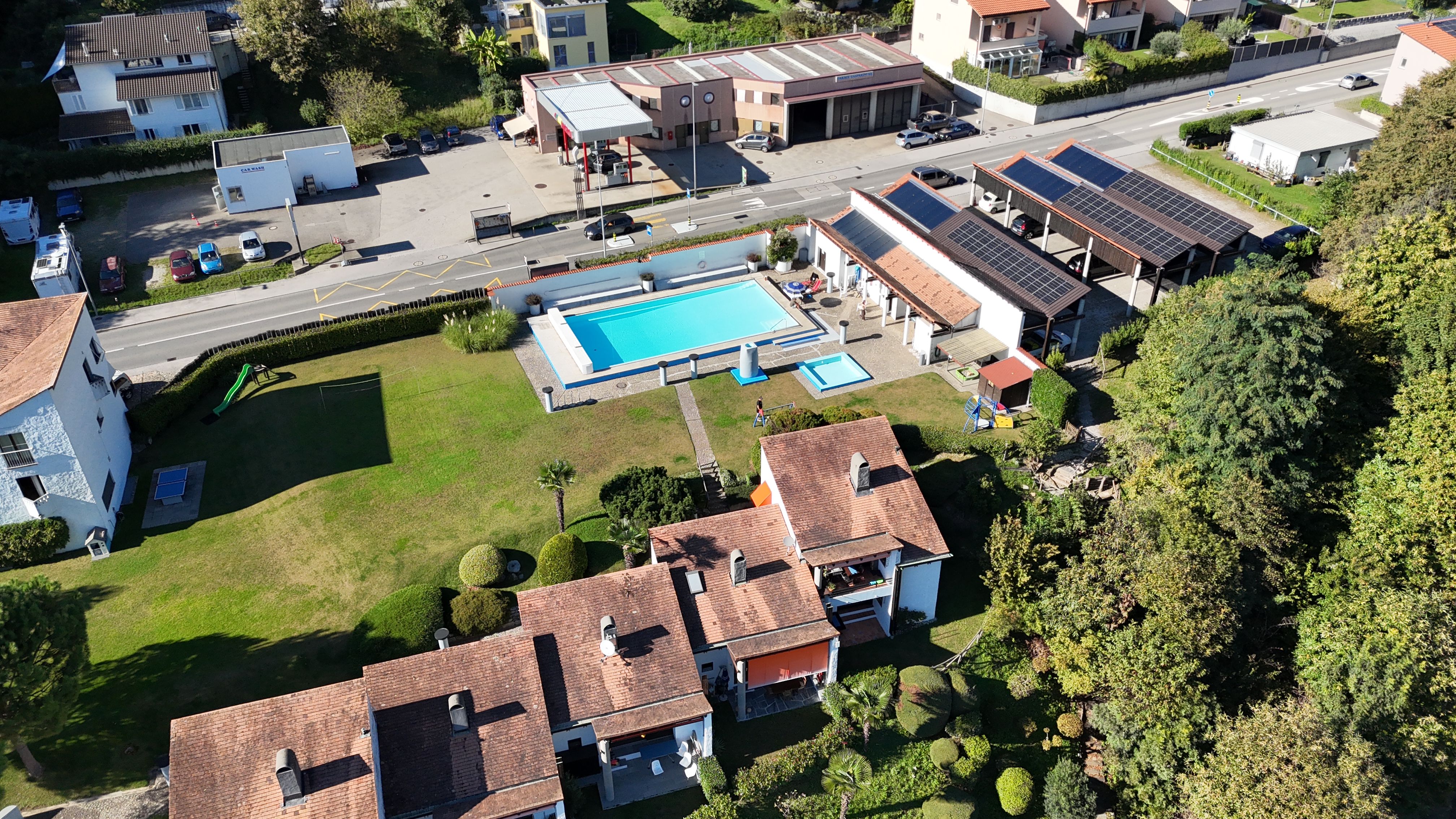 Luftaufnahme eines Wohn- und Freizeitareals mit Pool, Gärten und PV-Dächern