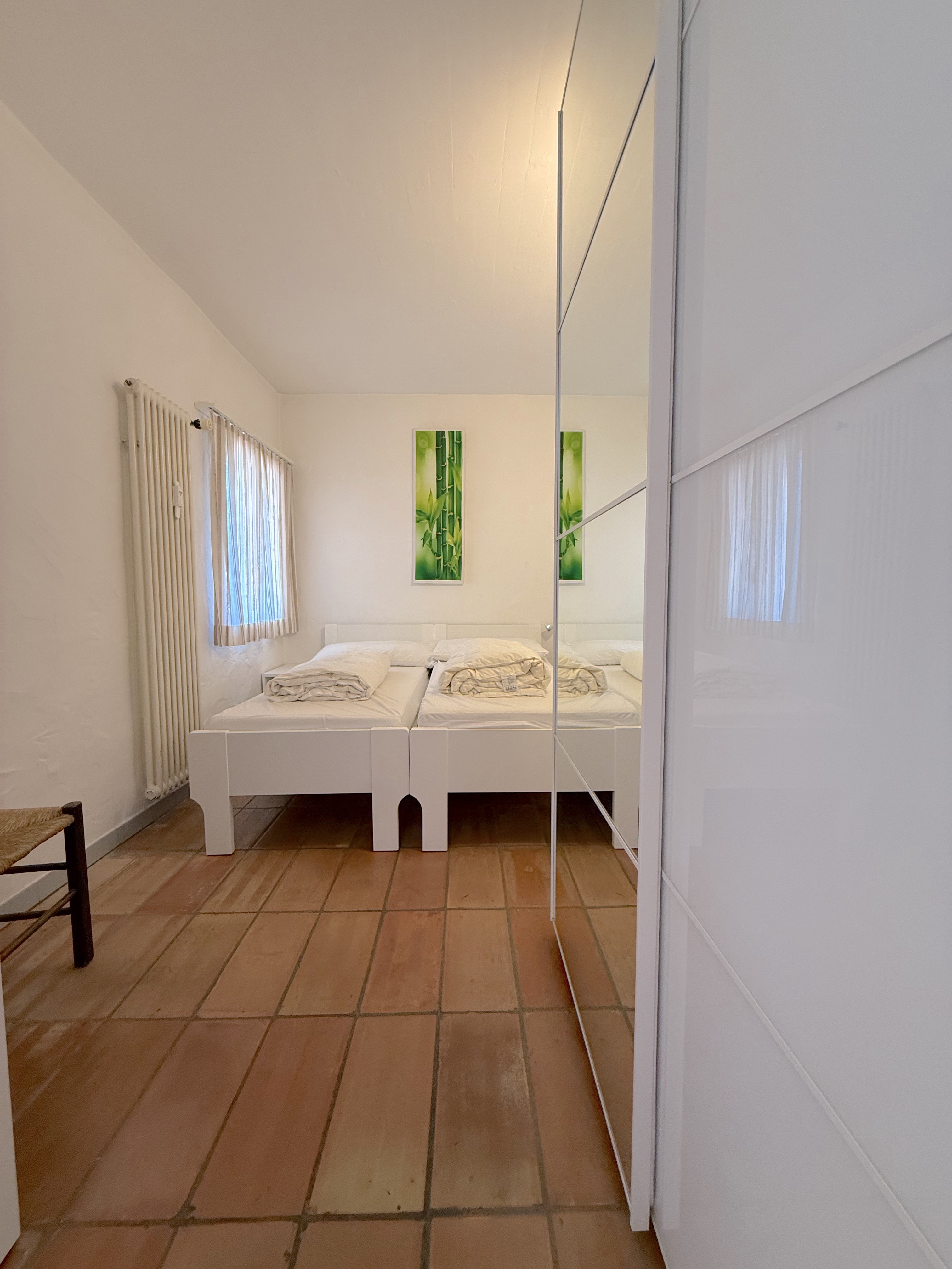Helles Schlafzimmer mit Schrankwand und Terrakottafliesen