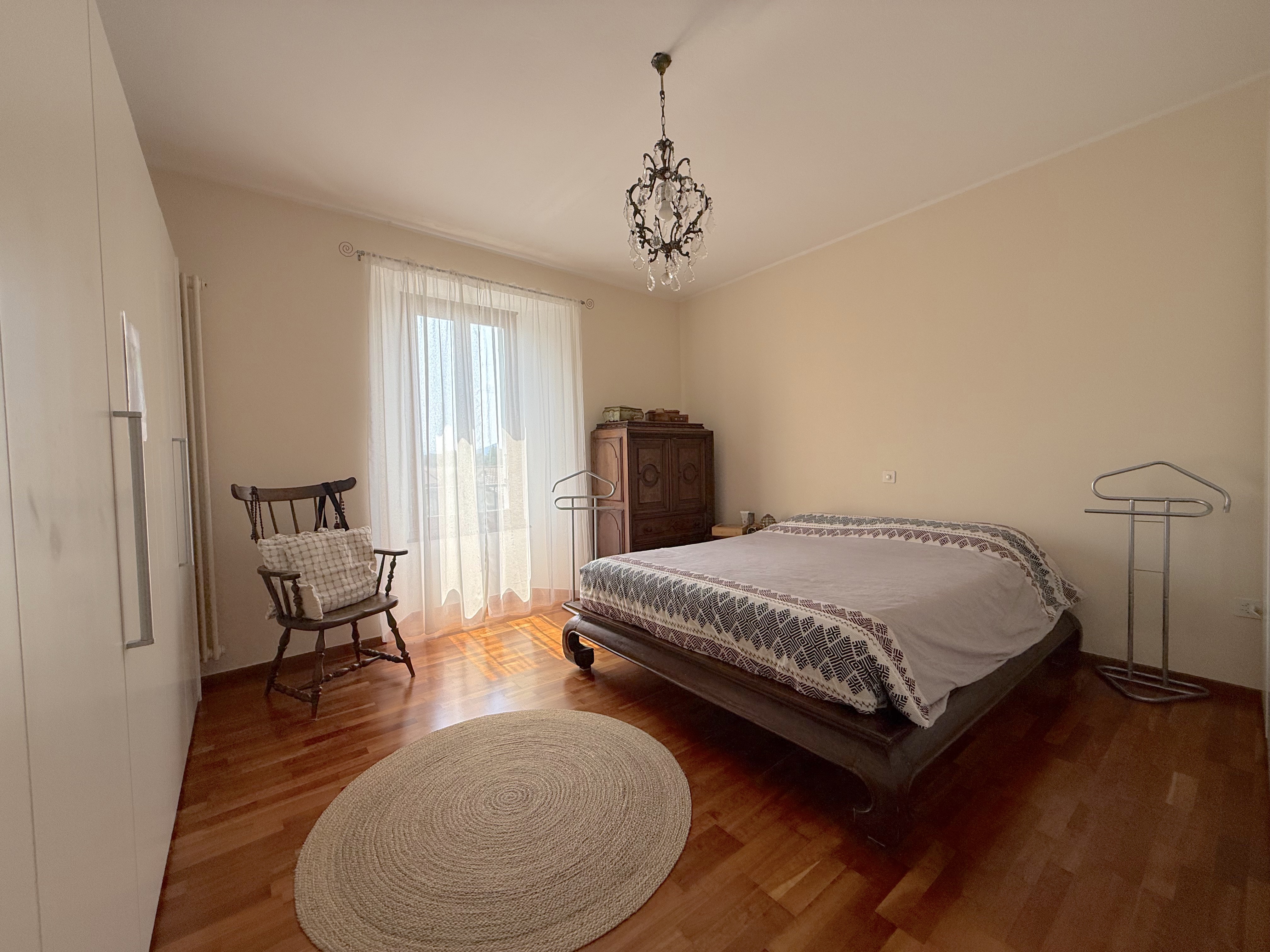 Helles Schlafzimmer mit Holzparkett und Kronleuchter