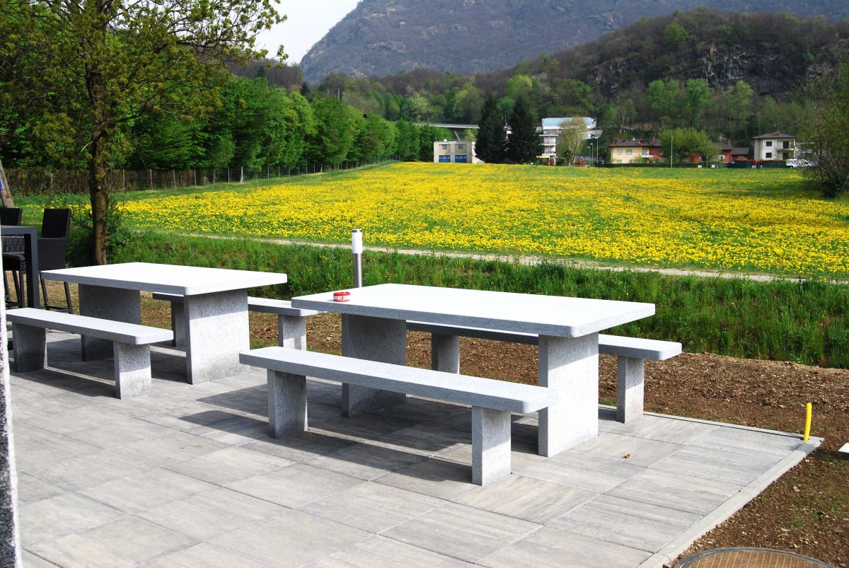 Außenbereich mit Picknicktischen vor Blumenwiese und Bergkulisse