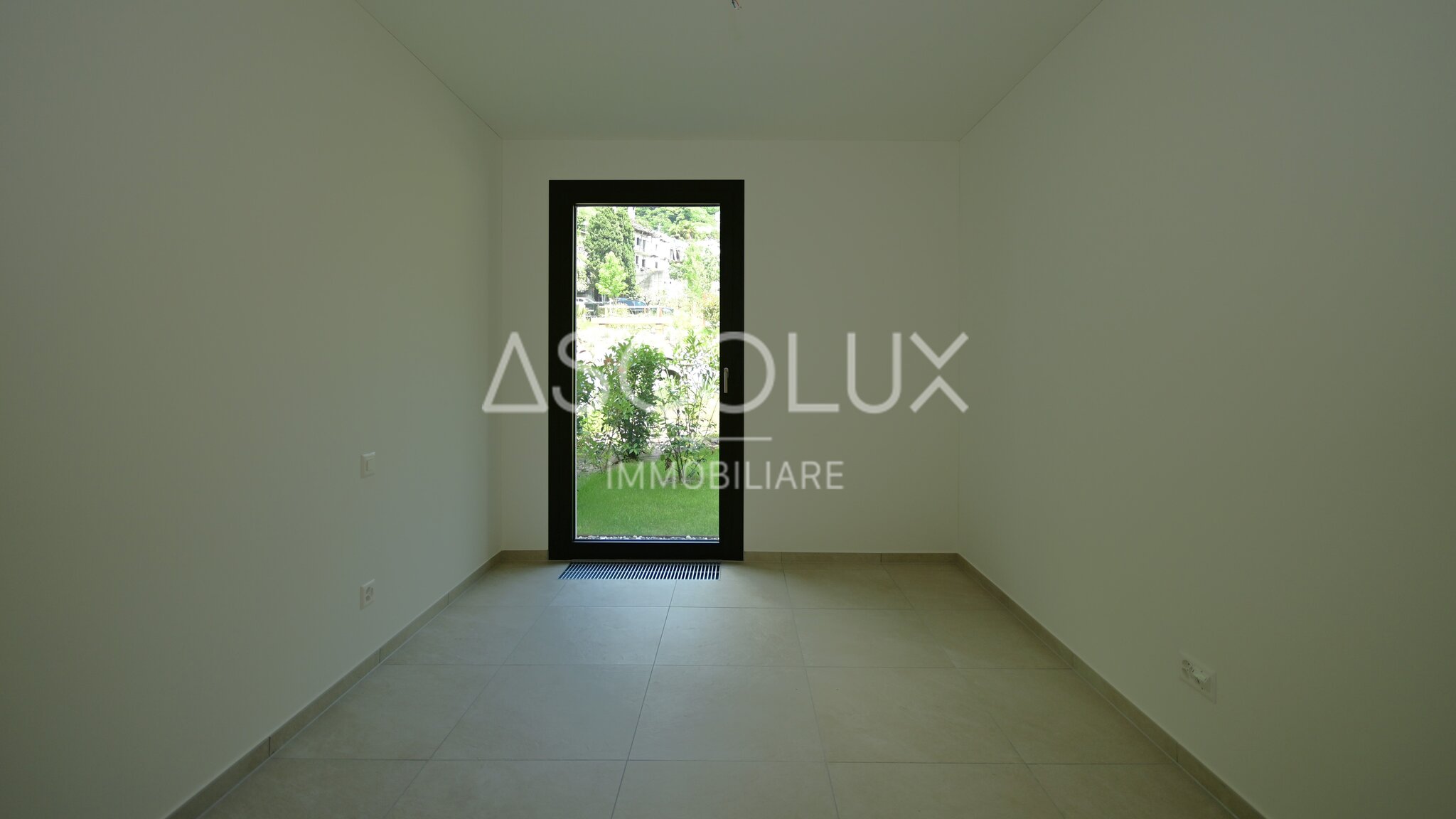 Leerer, heller Raum mit schmalem Fenster und Gartenblick