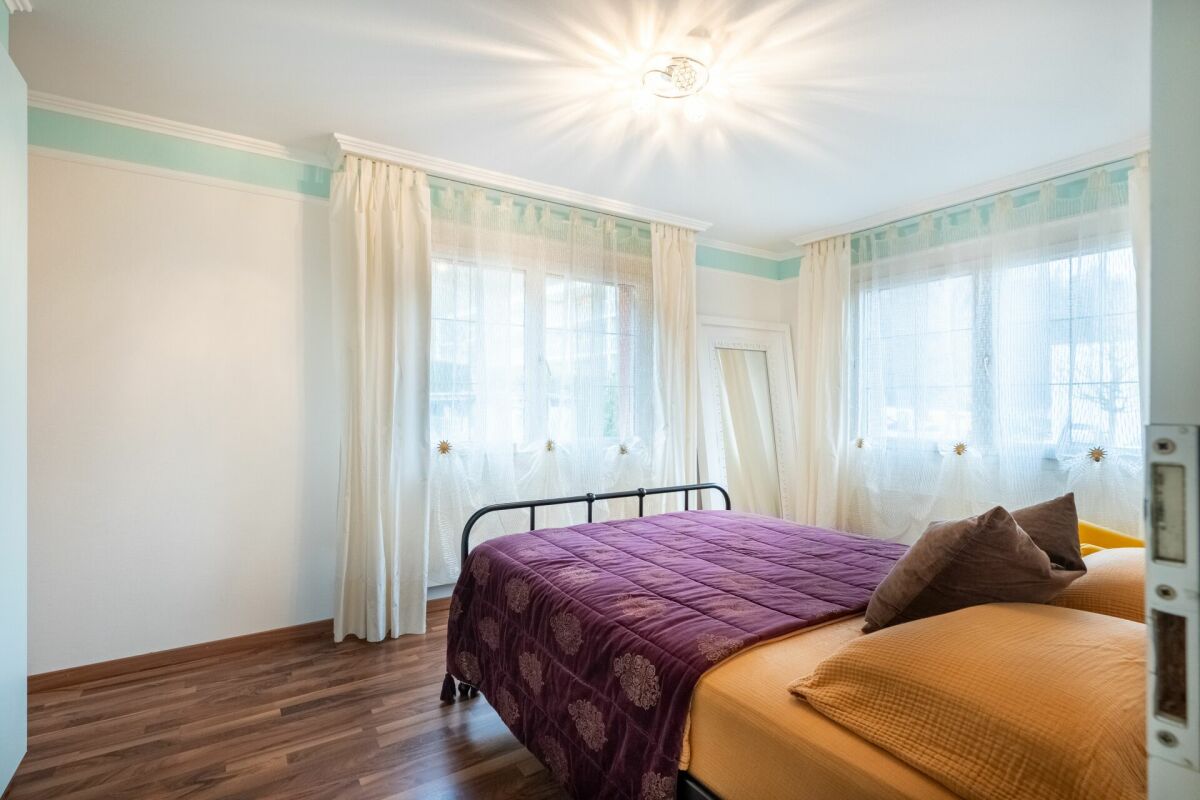 Helles Schlafzimmer mit großem Bett und zwei Fenstern
