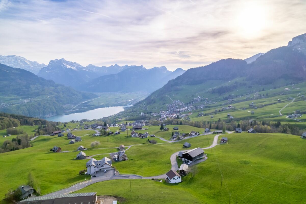 Luftaufnahme einer alpinen Landschaft mit See und verstreuten Höfen