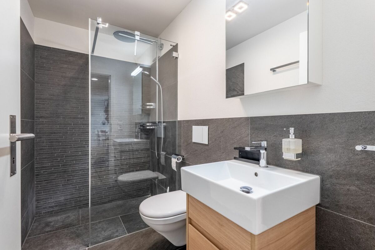Modernes Badezimmer mit Glasdusche und Waschplatz