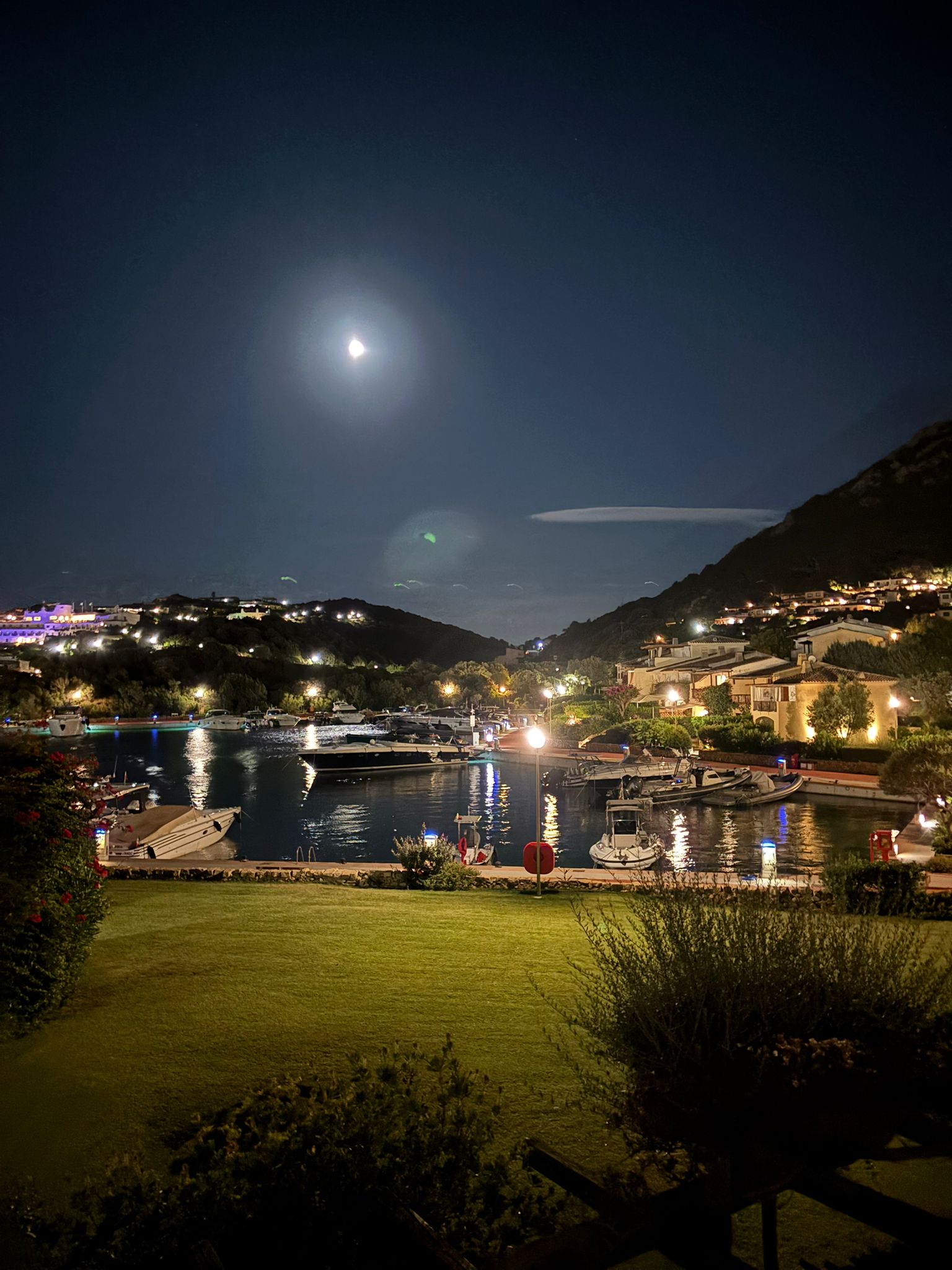 Nächtlicher Blick auf Yachthafen mit Bergen und Mond
