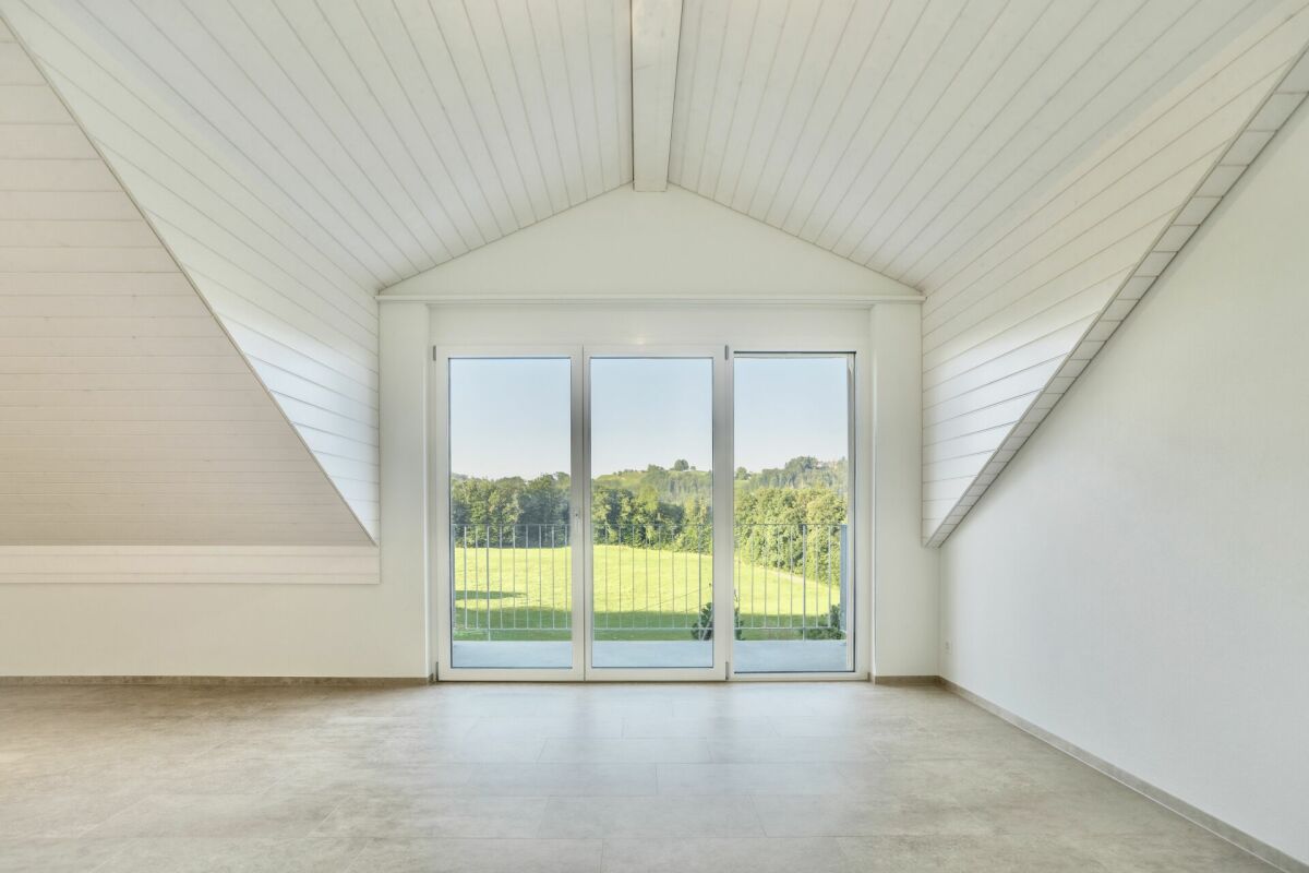 Dachgeschossraum mit großem Balkon- oder Terrassenelement und Grünblick