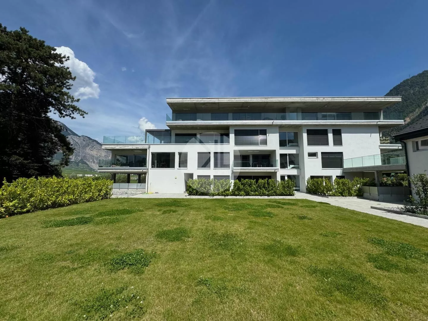 Modernes Mehrfamilienhaus mit Garten und Bergkulisse