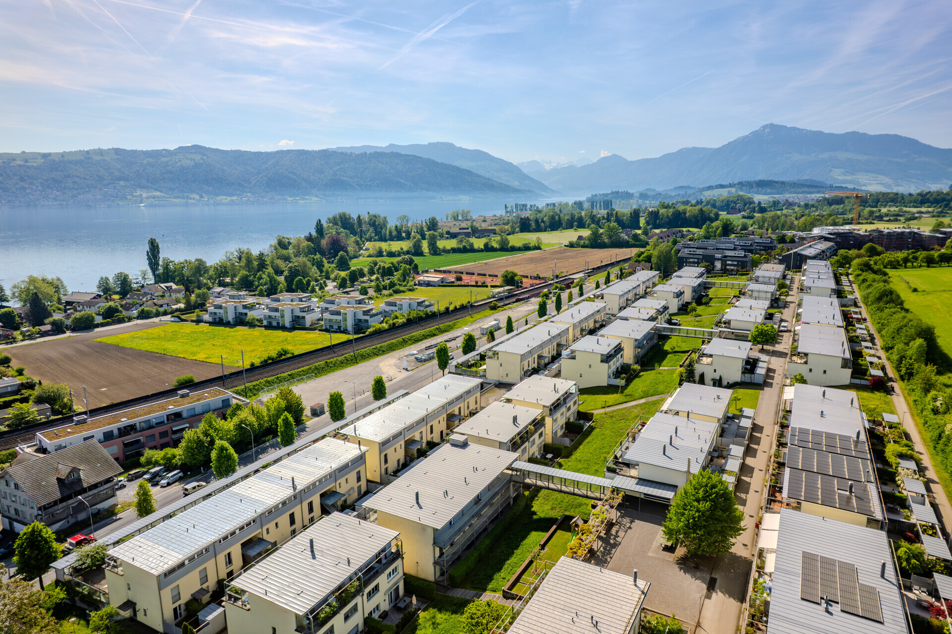 Luftaufnahme einer Wohnanlage am See mit Bergpanorama
