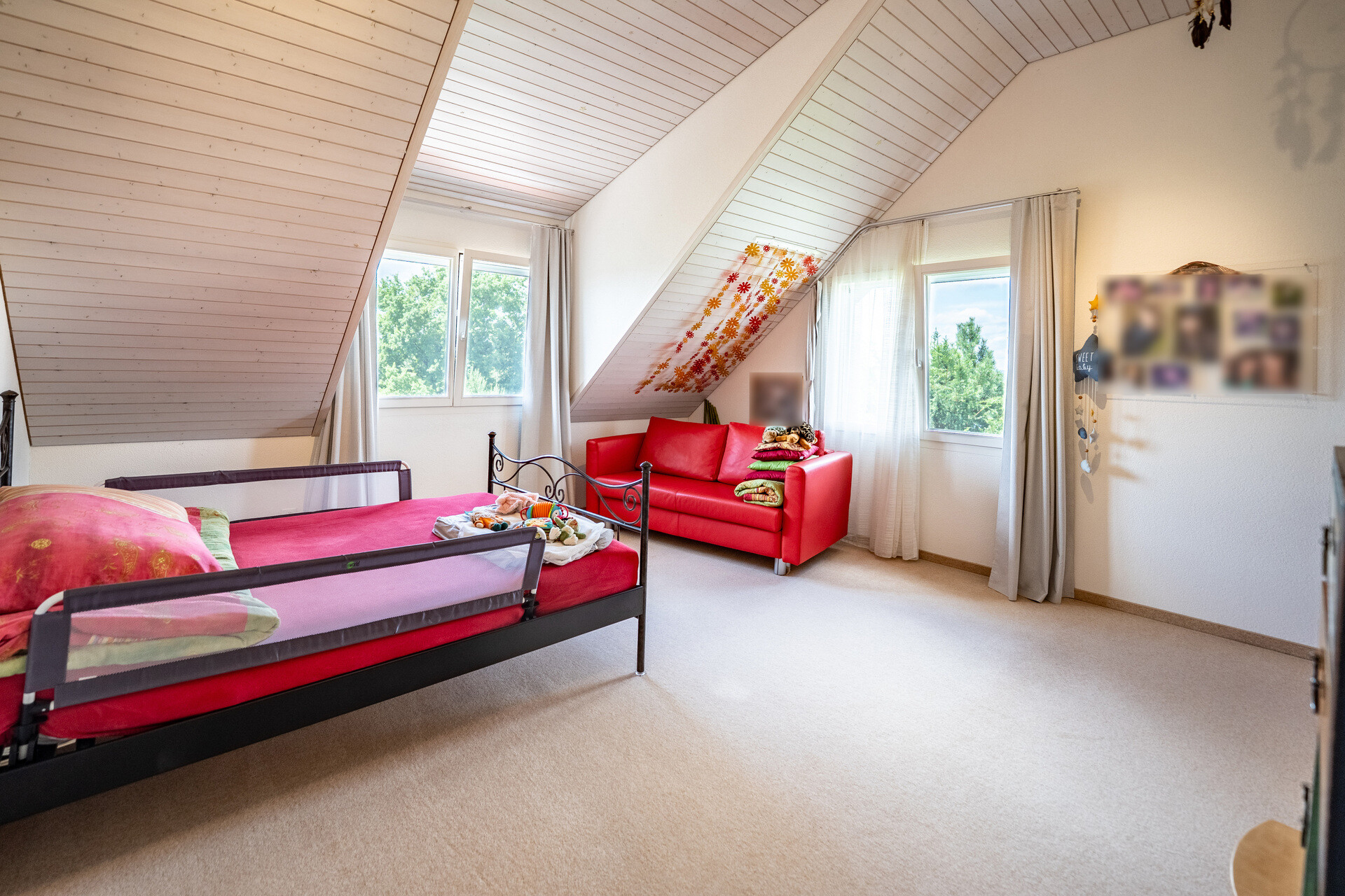 Dachzimmer mit Bett und rotem Sofa
