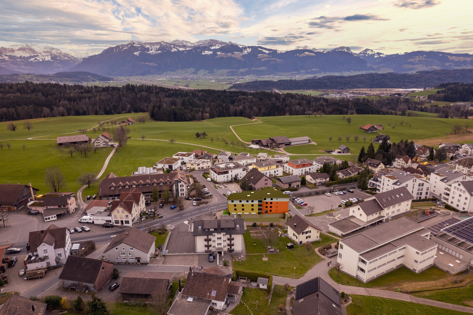 Luftaufnahme eines Wohnortes mit Alpenpanorama