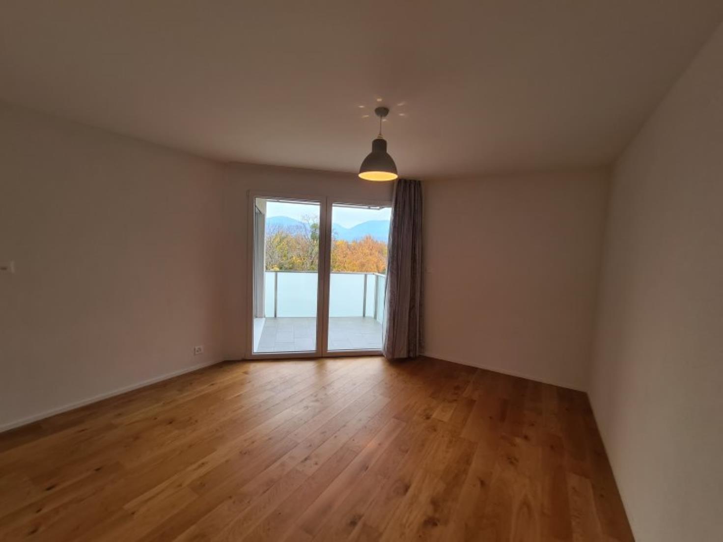 Leerer Wohnraum mit Balkon und Bergblick