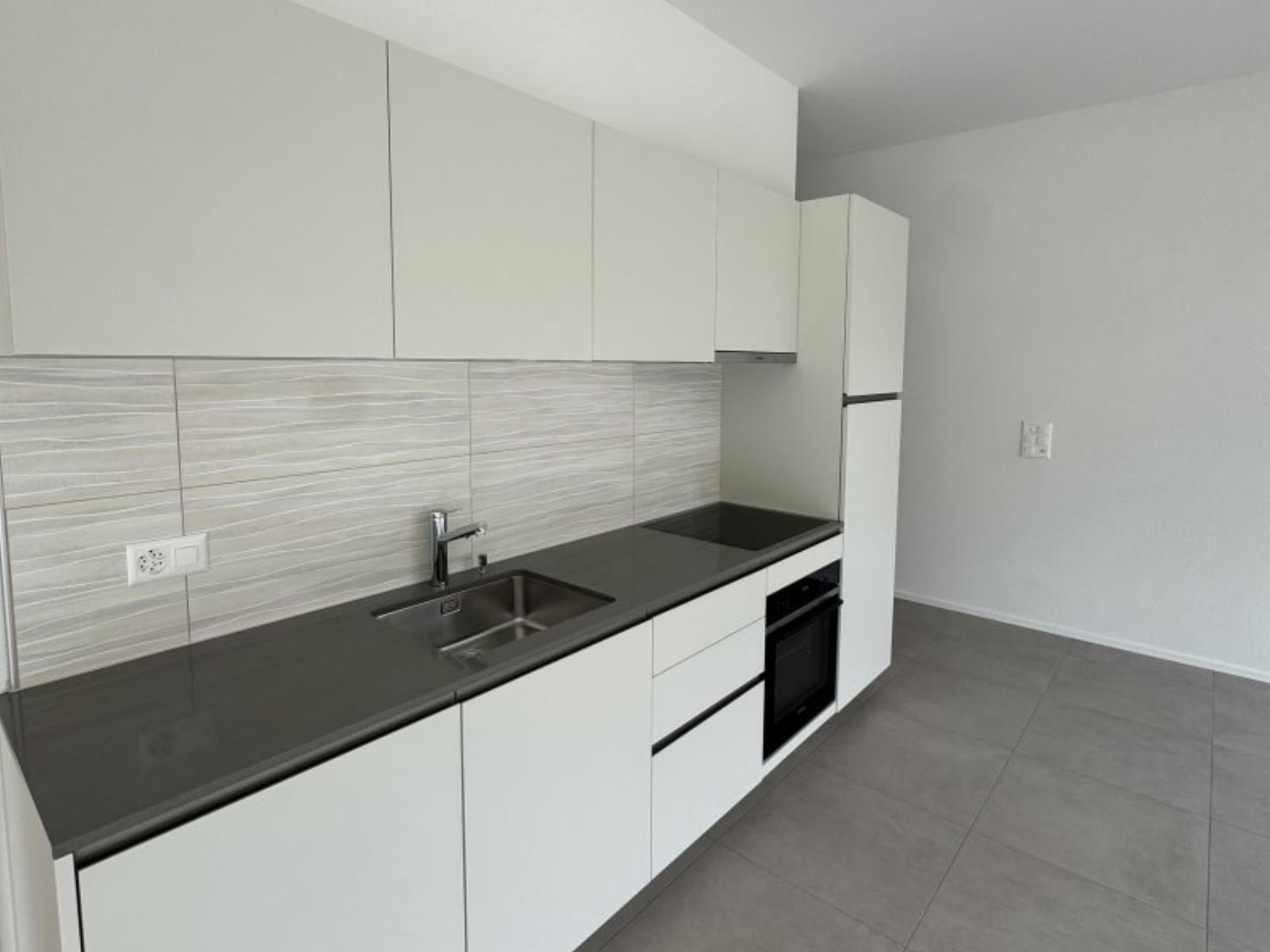 Moderne Küche mit weißen Fronten und dunkler Arbeitsplatte