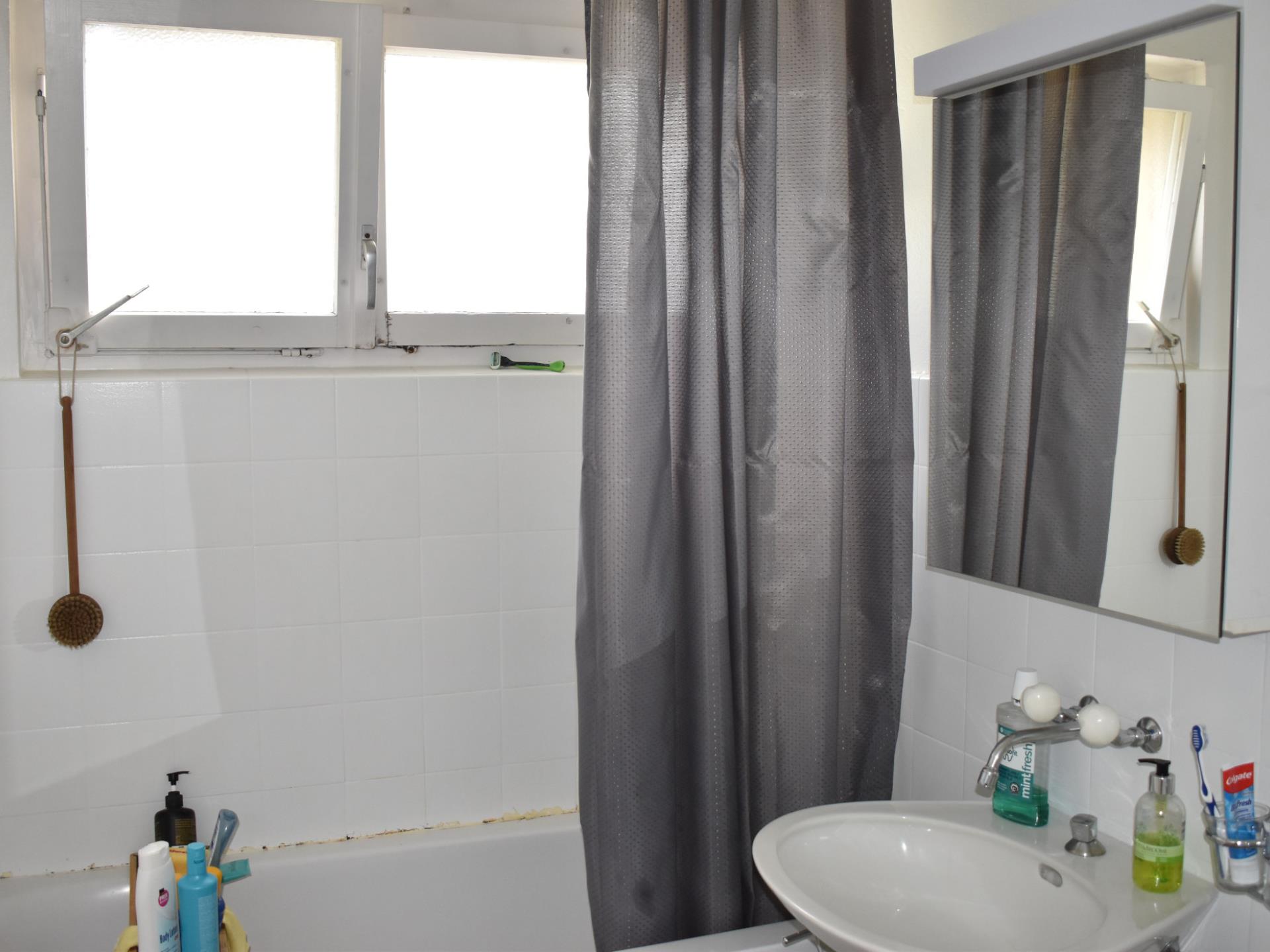 Badezimmer mit Wanne, Fenster und Waschbecken