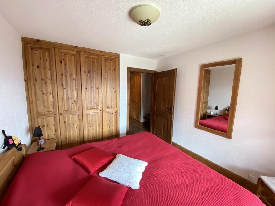 Schlafzimmer mit Holzschrank und rotem Bett