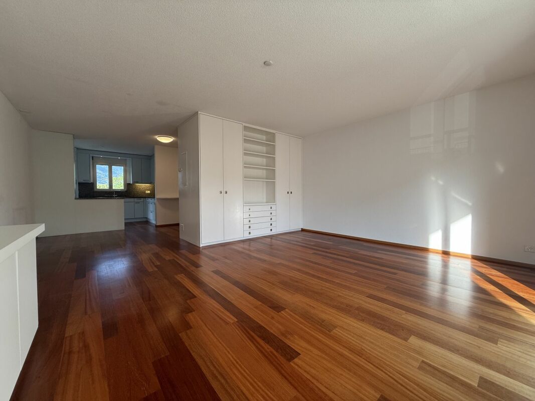 Heller leerer Wohnraum mit Einbauschrank und Blick zur Küche