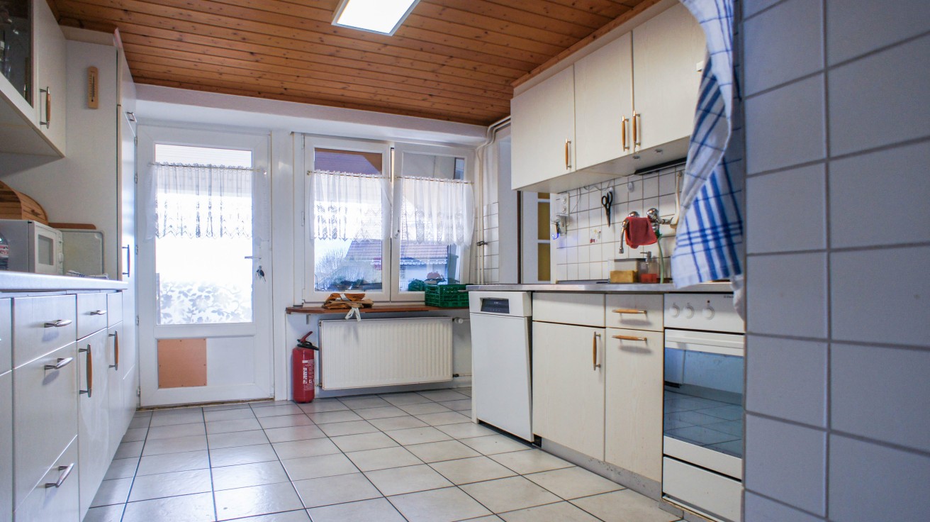 Helle, einfache Küche mit Holzdecke und Fliesenboden
