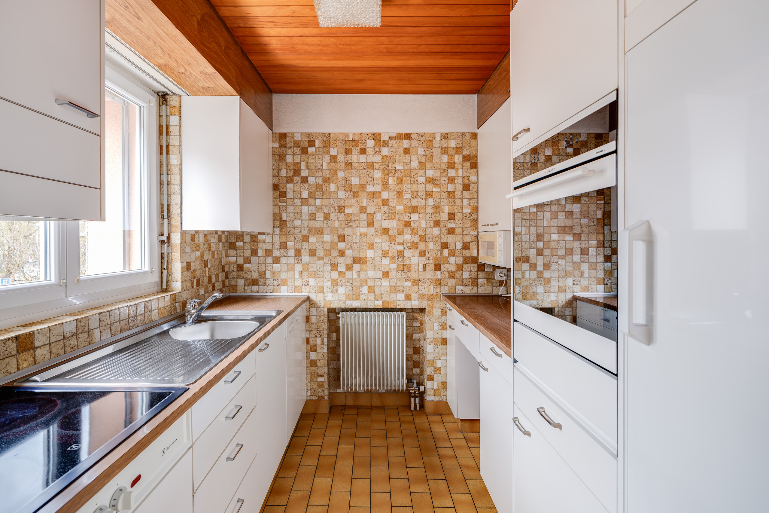 Schmale Küche mit Holzdecke und Mosaikfliesen