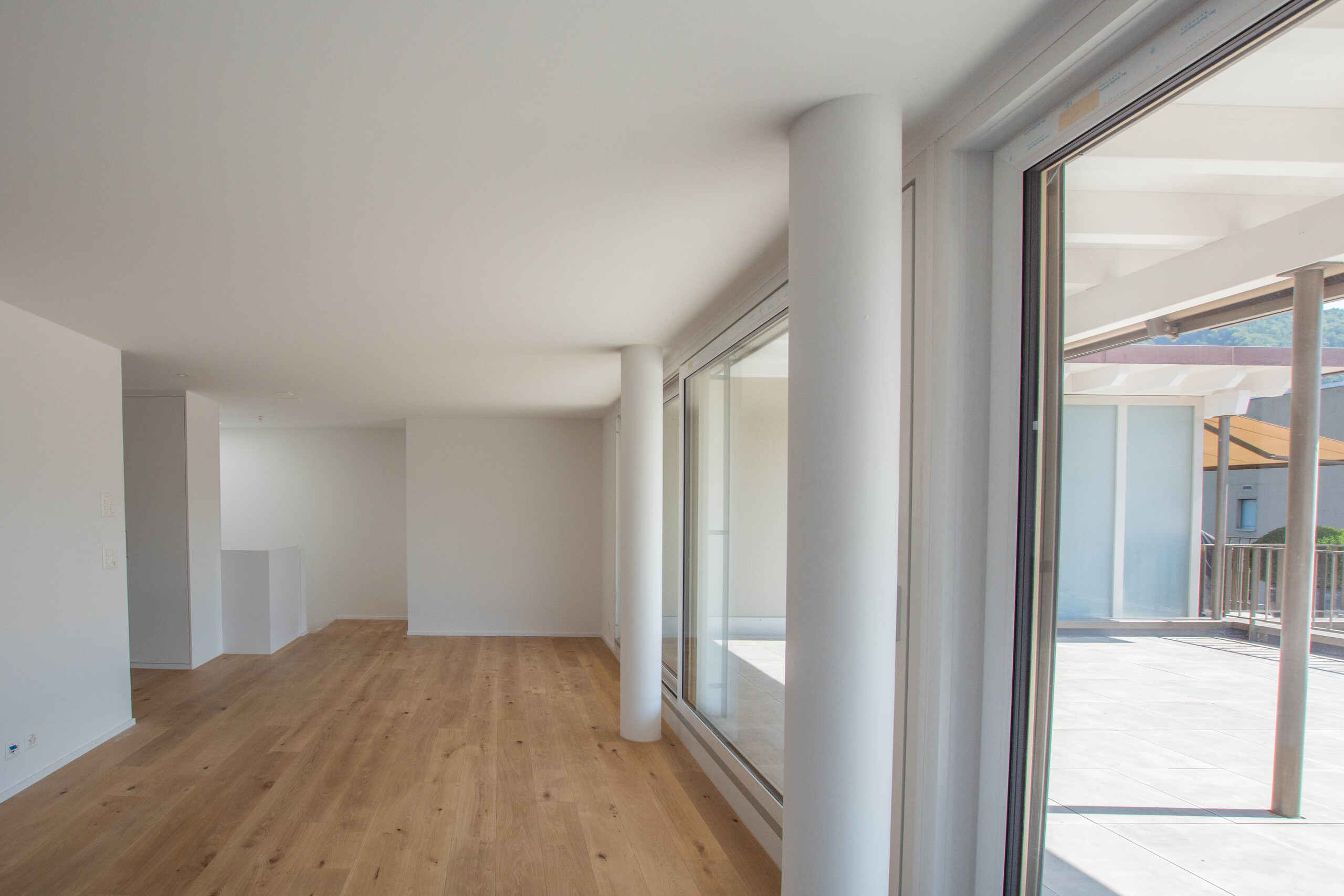 Heller, leerer Innenraum mit Holzfußboden und großen Glasflächen