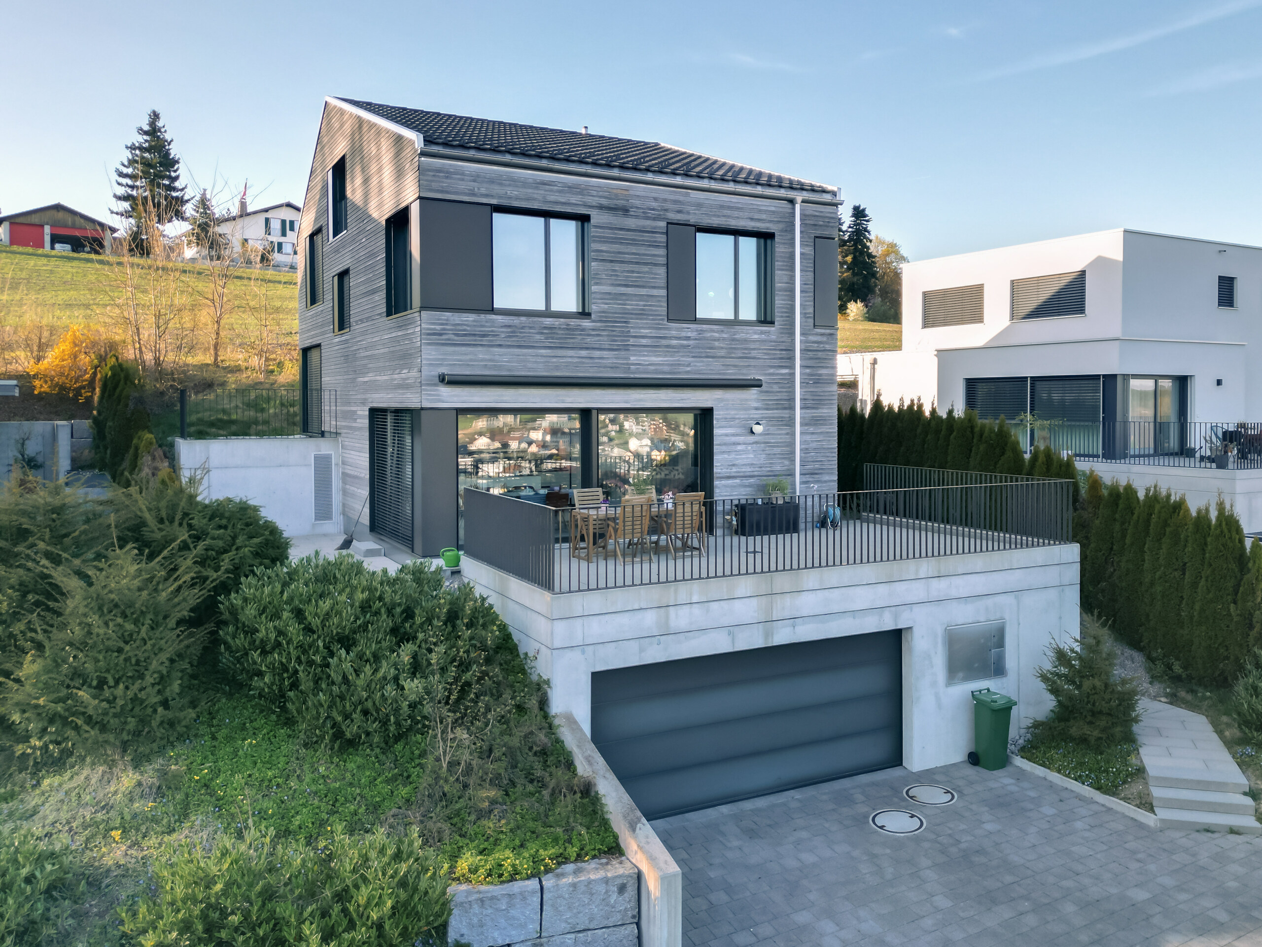 Moderne Einfamilienhaus-Ansicht mit Terrasse und Garagenzufahrt