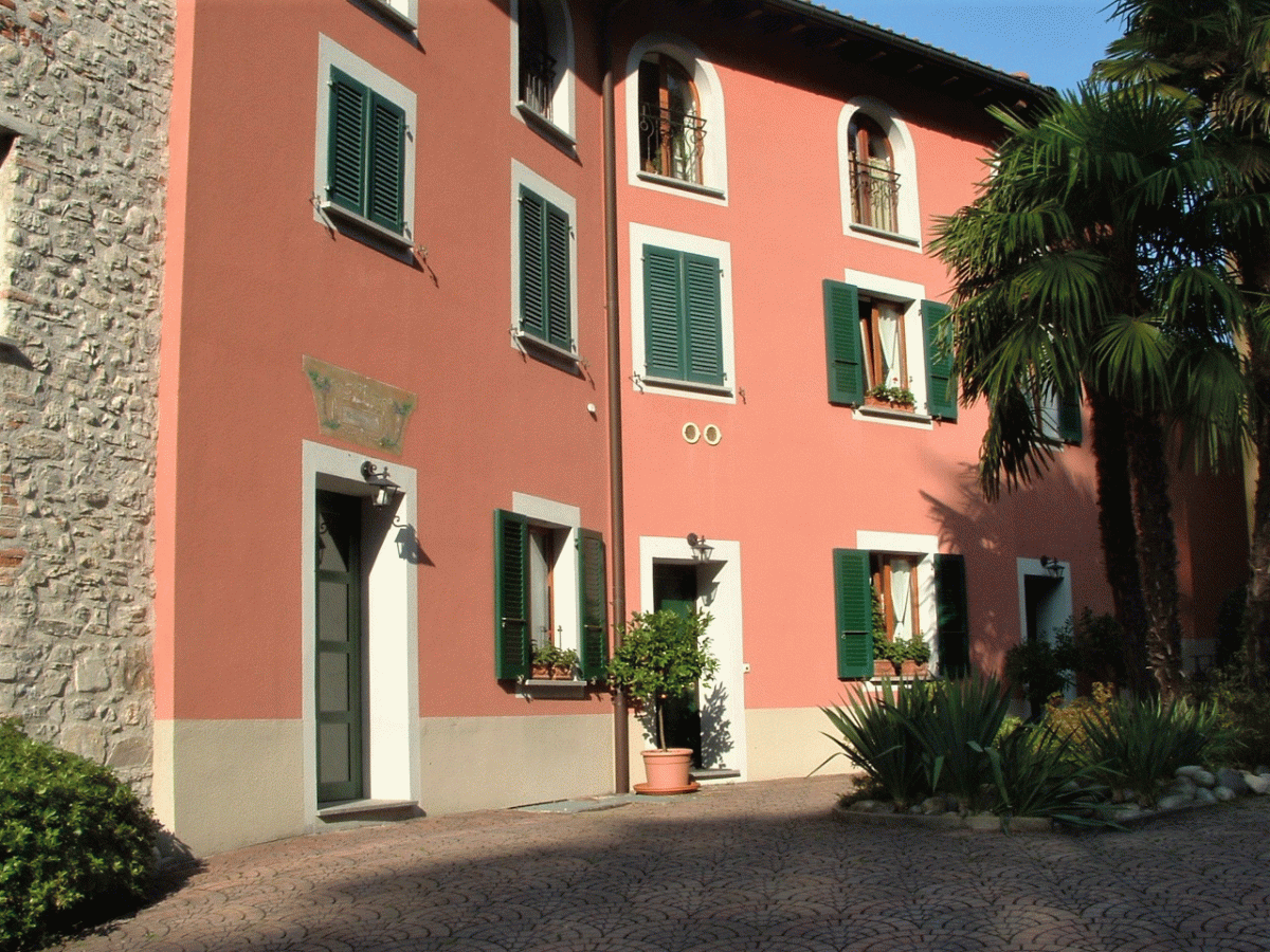 Pastellfarbene Villenfassade mit grünen Fensterläden