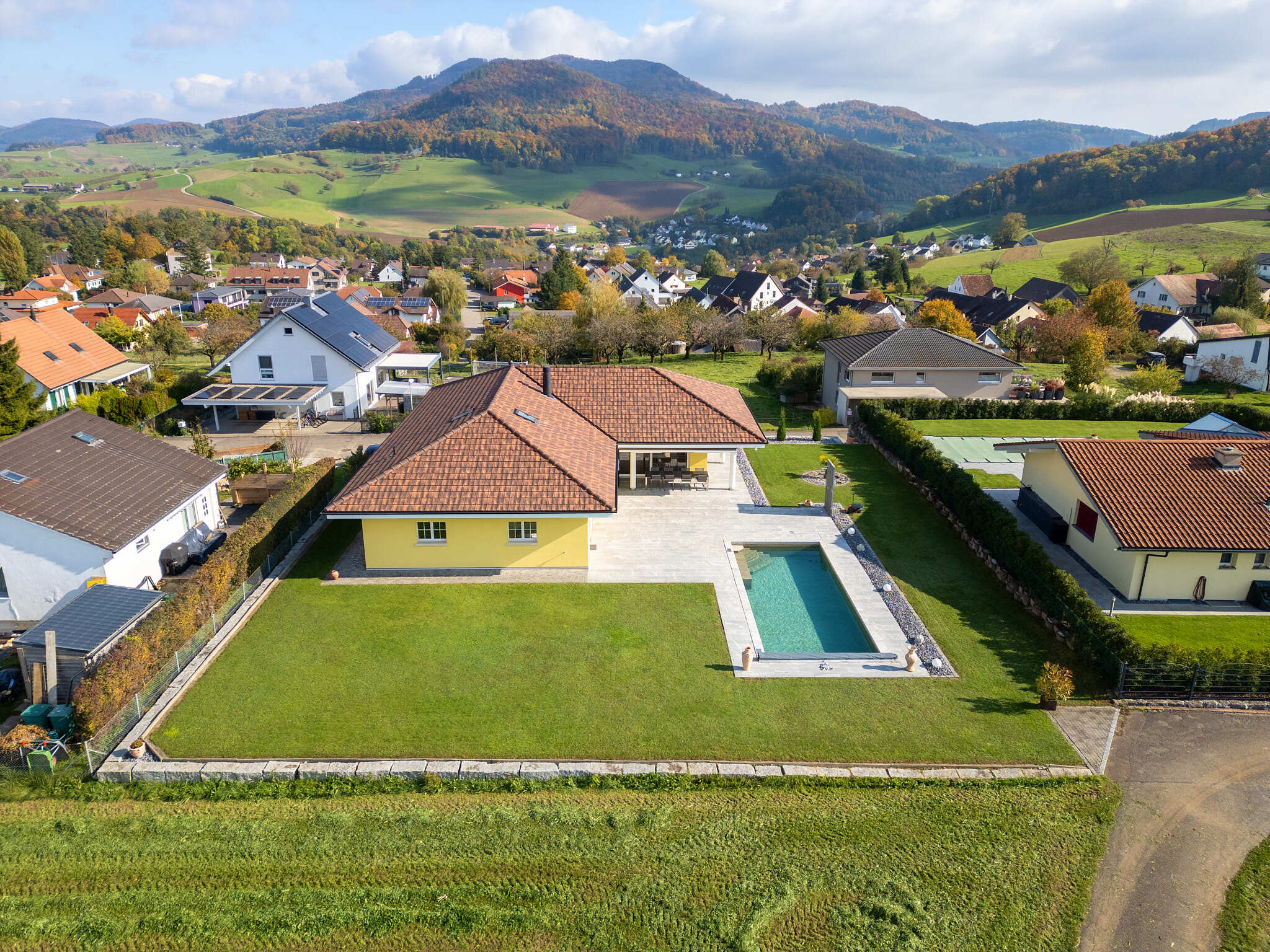 Luftaufnahme eines Einfamilienhauses mit Pool und Bergblick