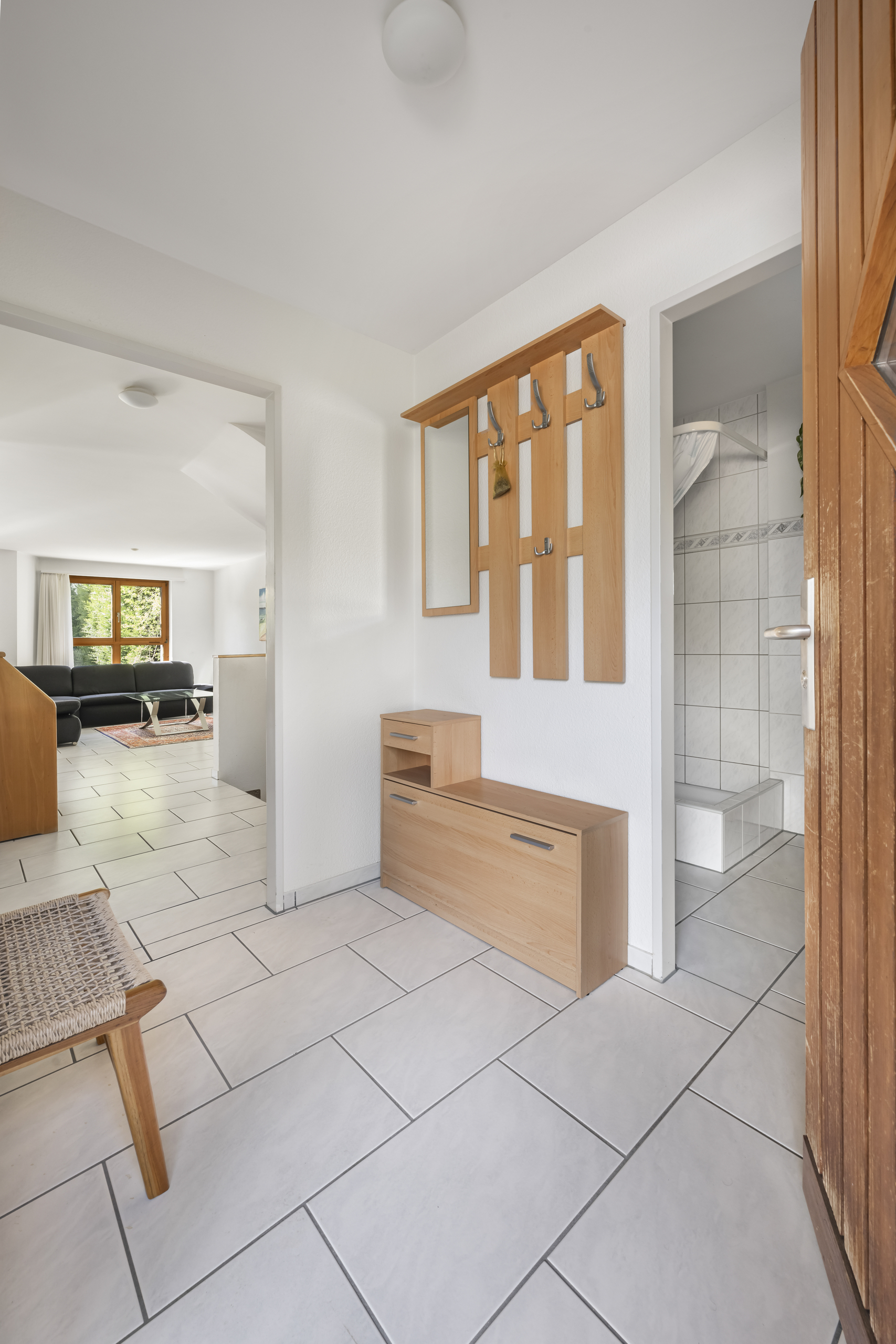 Heller Eingangsbereich mit Blick ins Wohnzimmer und kleines Badezimmer