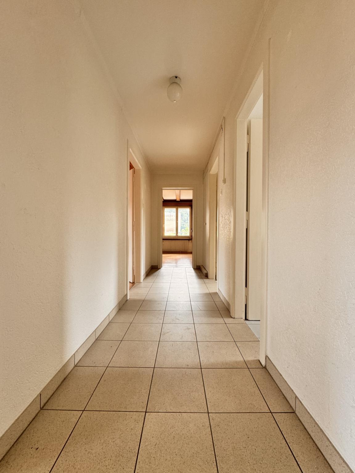 Langer Flur mit Türen und Fenster am Ende