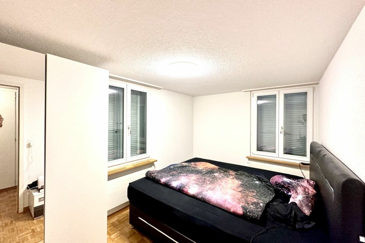 Schlafzimmer mit Doppelbett und zwei Fenstern