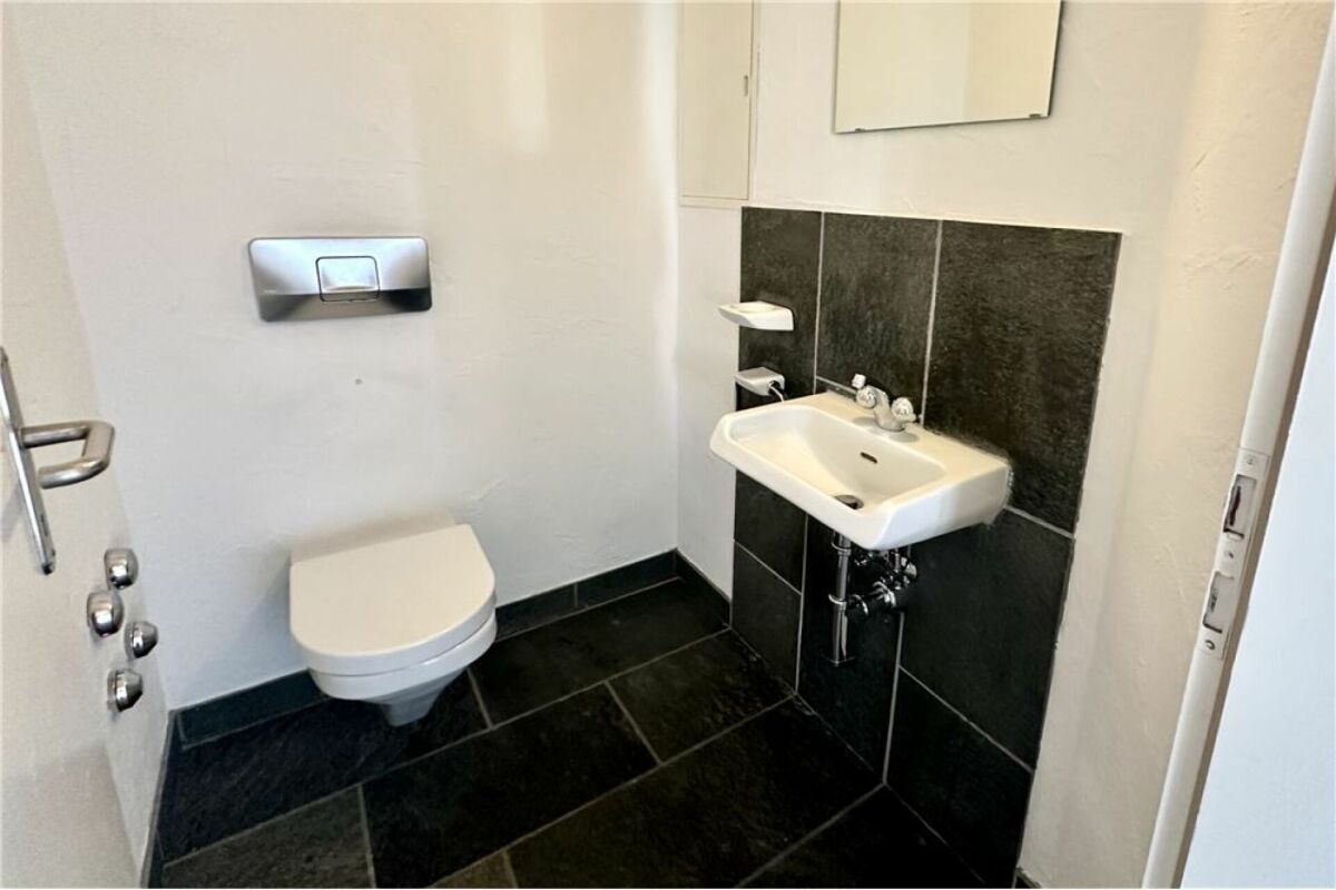 Kleines Gäste-WC mit dunklem Boden und Wand-WC