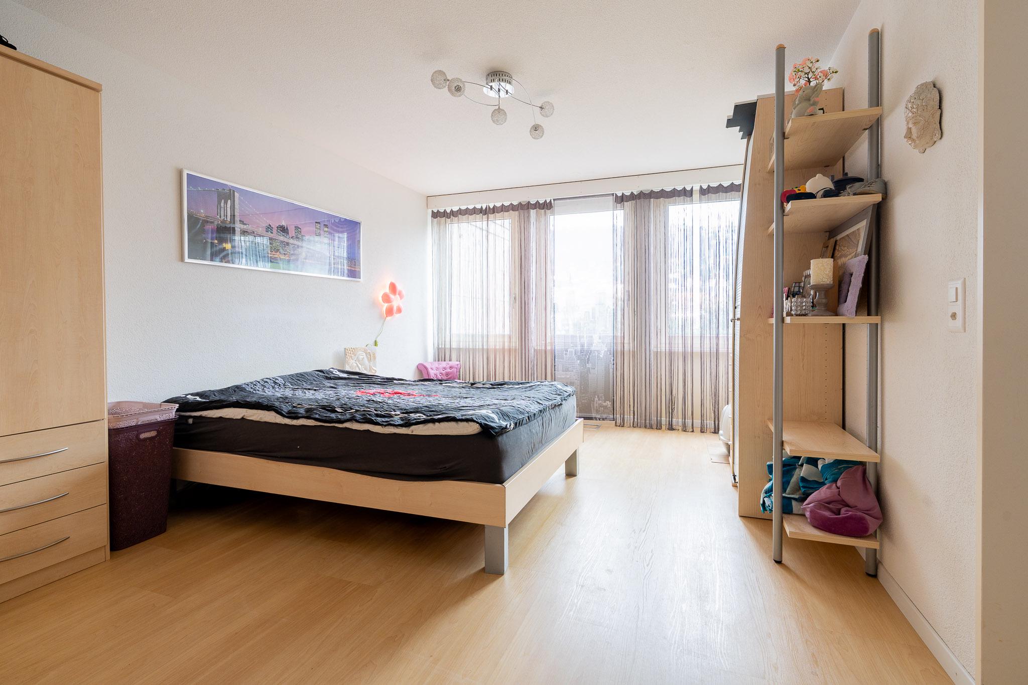 Helles Schlafzimmer mit Doppelbett und Fensterfront
