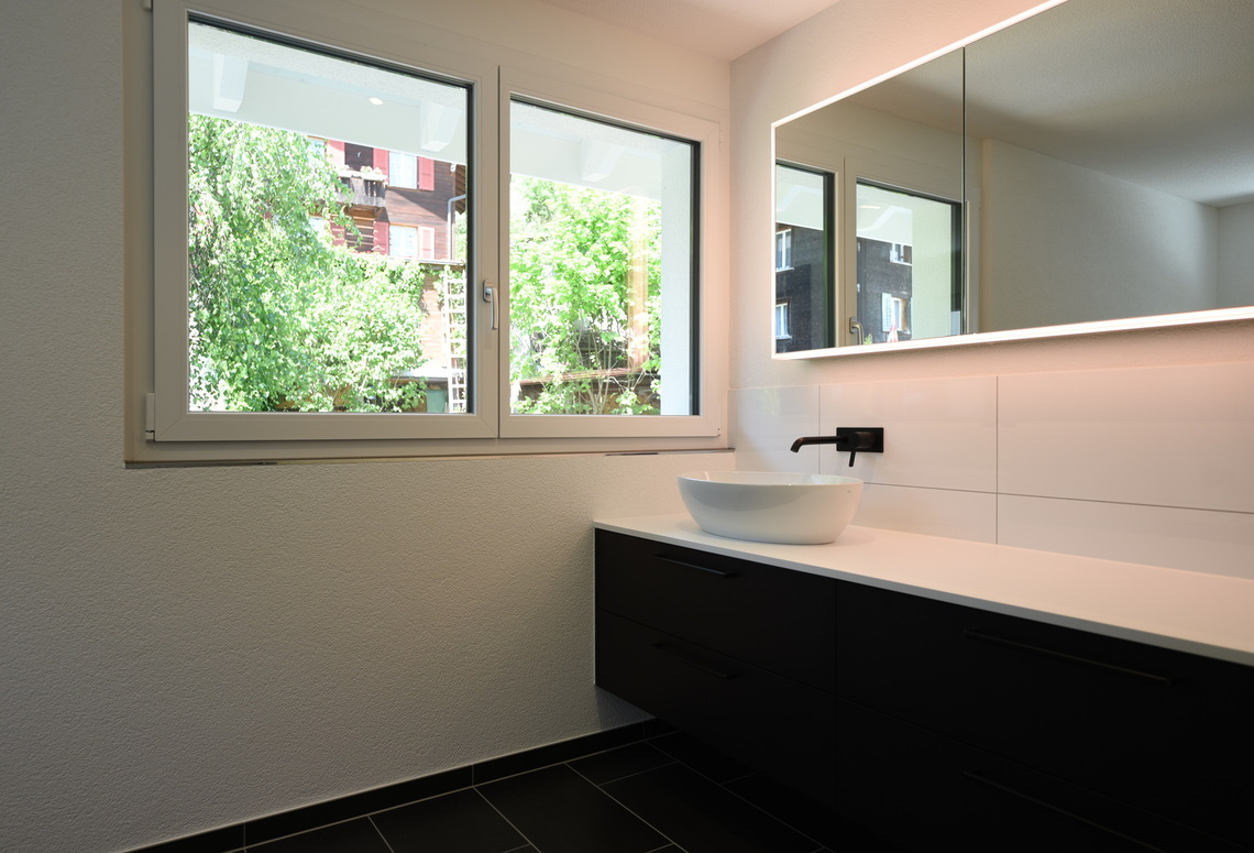 Modernes Badezimmer mit Fenster und beleuchtetem Spiegelschrank
