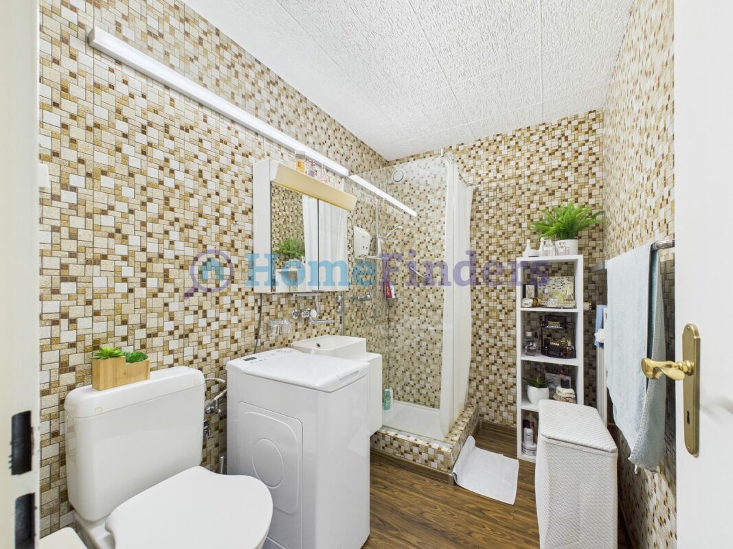 Kompaktes Badezimmer mit Mosaikfliesen und Waschtrockner