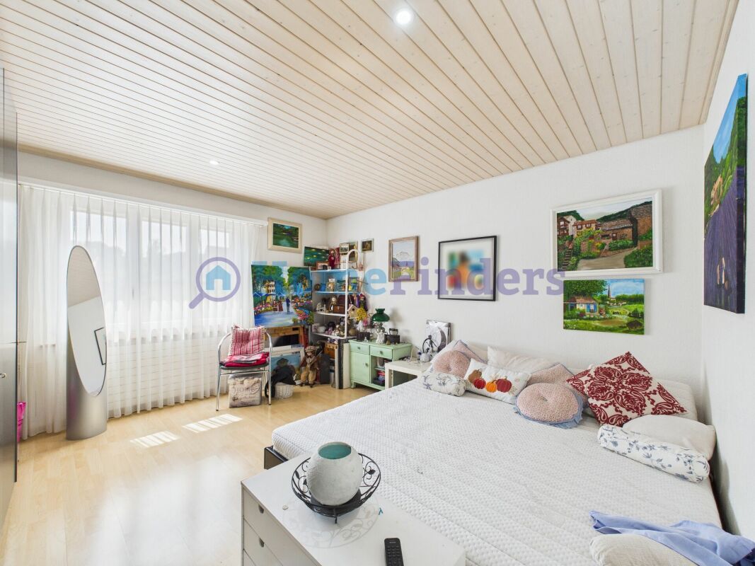 Helles Schlafzimmer mit Fenster, Bett und Kunstwerken