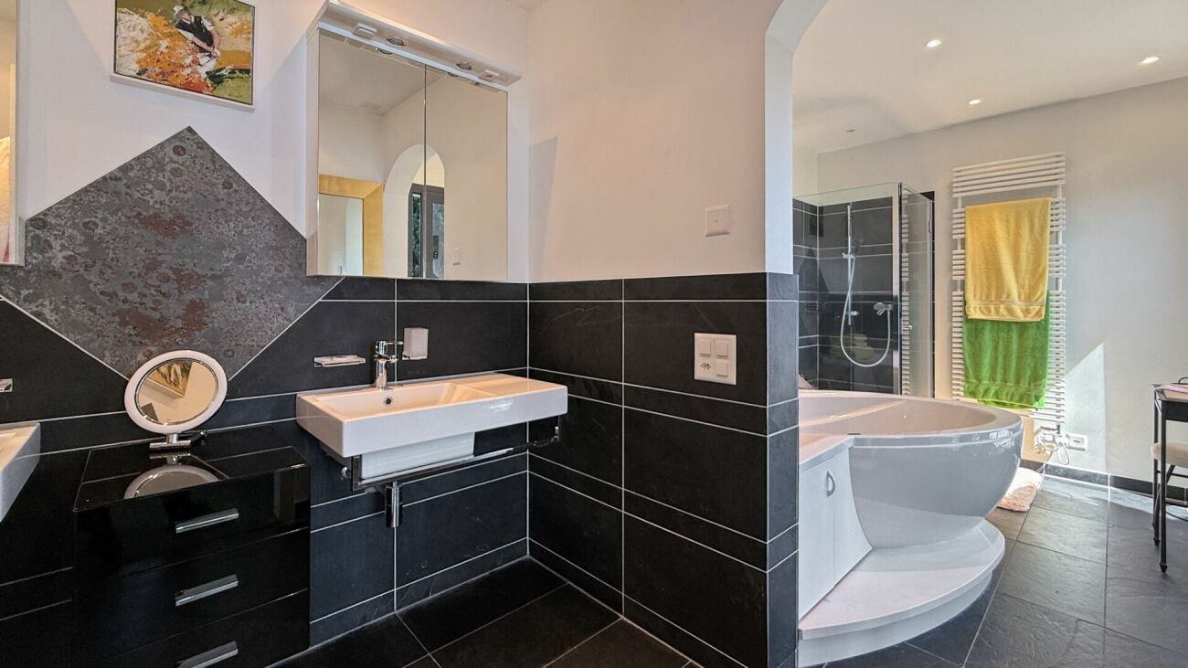 Modernes Badezimmer mit schwarzer Wandverkleidung und großer Badewanne