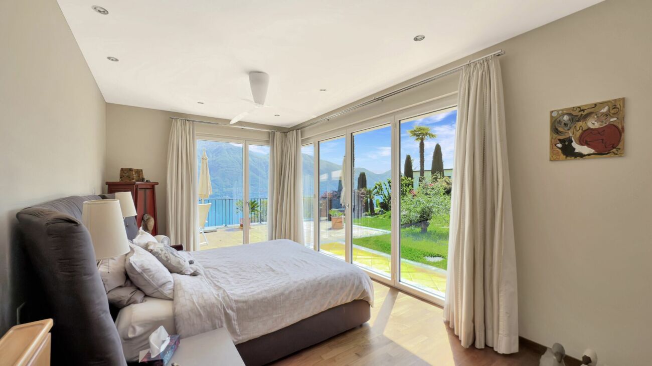 Schlafzimmer mit großer Fensterfront und Gartenblick