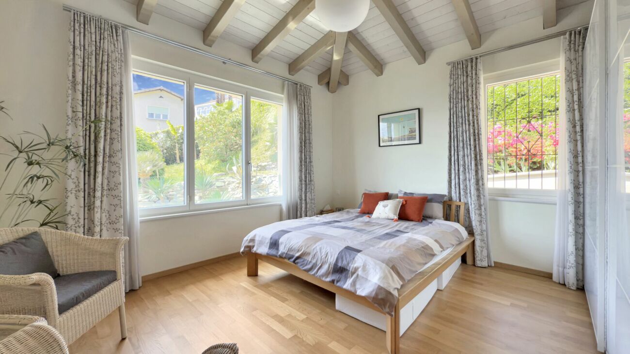 Helles Schlafzimmer mit Holzdecke und Gartenblick