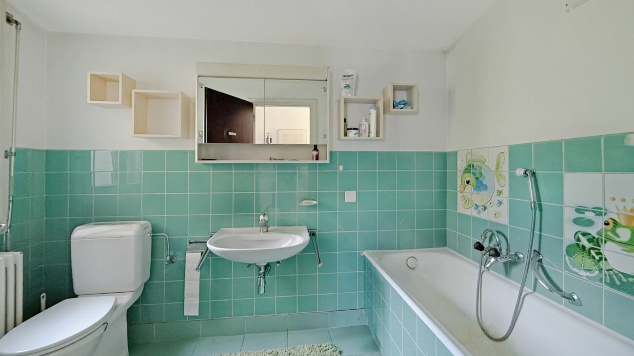 Türkisfarbenes Badezimmer mit Badewanne und WC