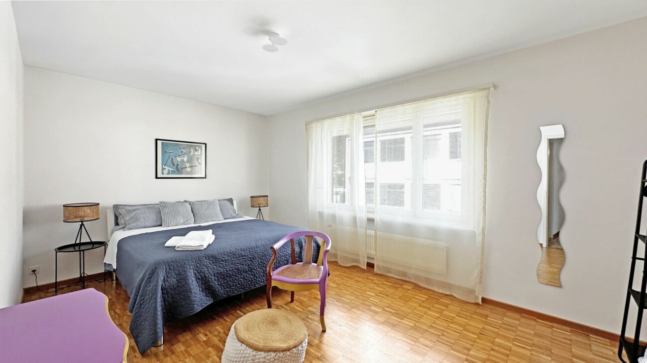 Schlafzimmer mit großem Fenster und heller Einrichtung