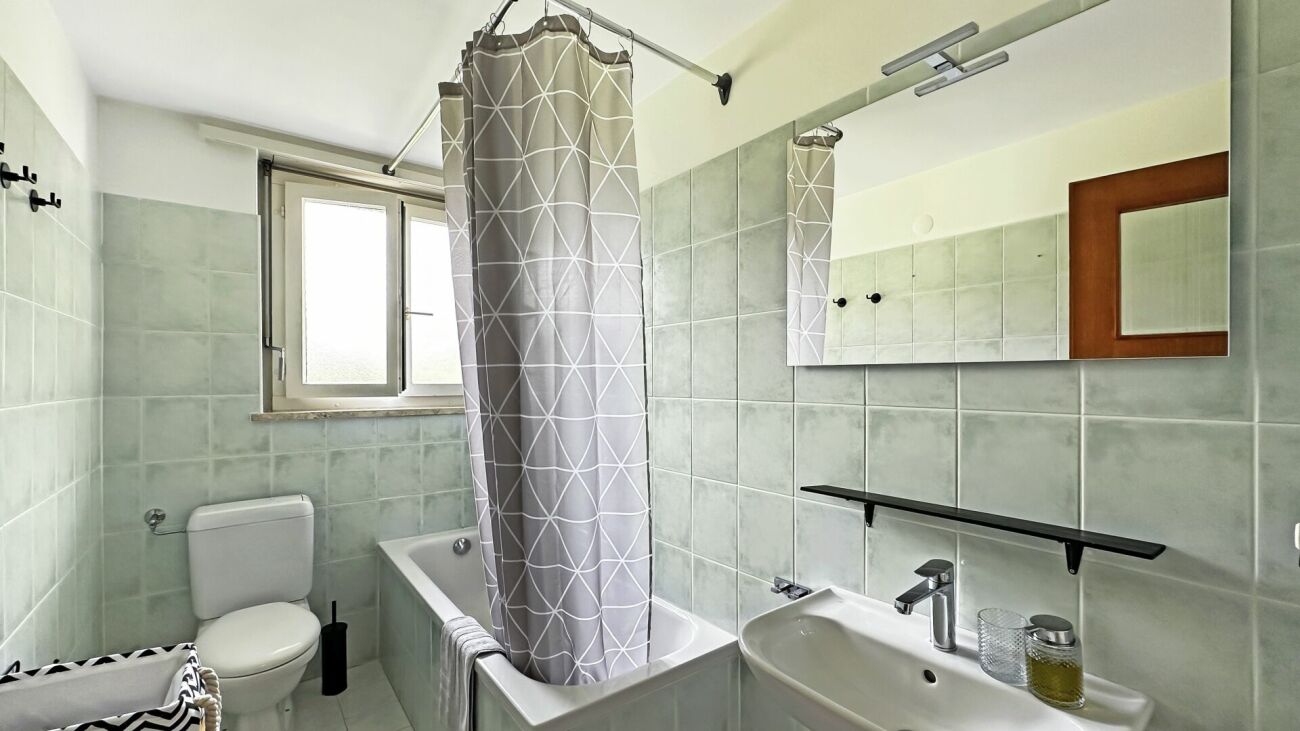 Modernes kleines Badezimmer mit Badewanne, Waschbecken, WC und Fenster
