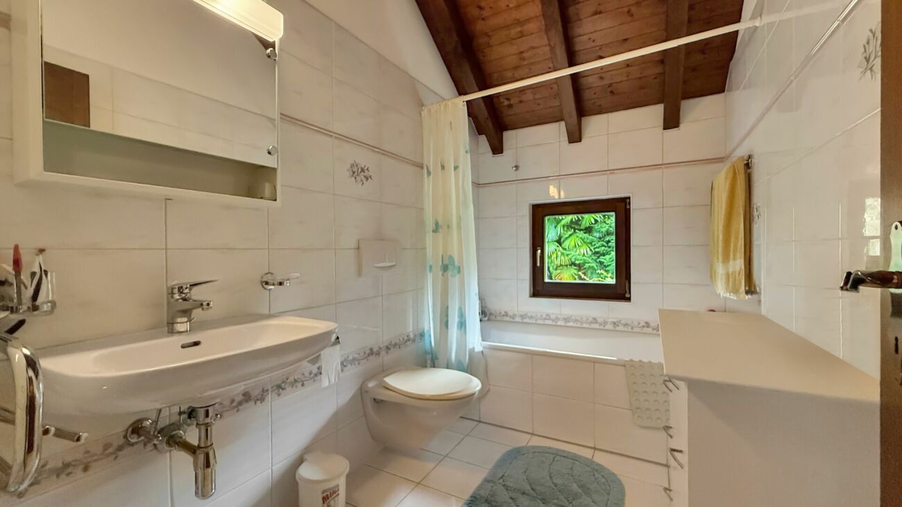 Badezimmer mit Badewanne und Holzdecke