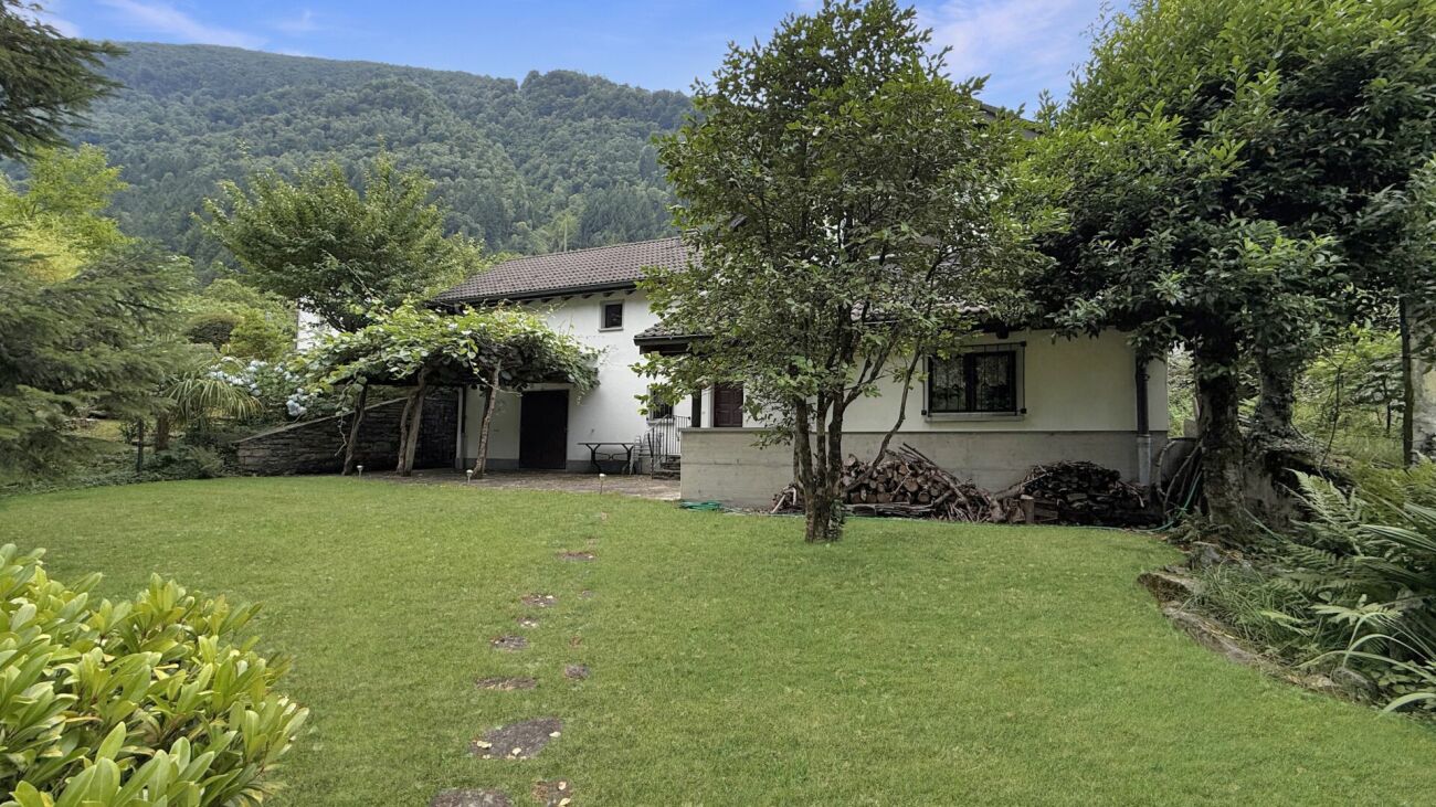 Haus mit großzügigem Garten vor bewaldetem Berghang
