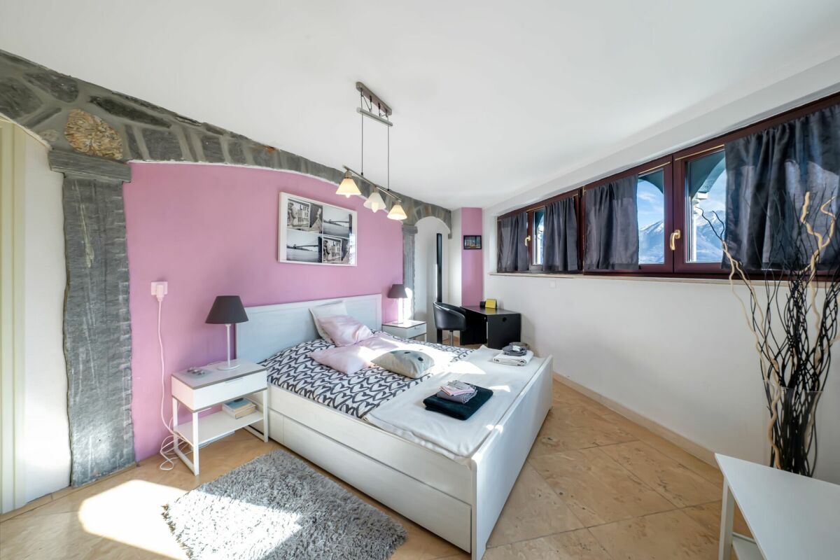 Schlafzimmer mit rosafarbener Akzentwand und Blick auf die Berge