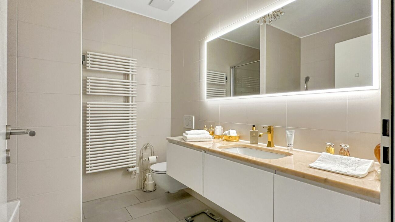 Modernes Badezimmer mit beleuchtetem Spiegel und Doppelwaschplatz