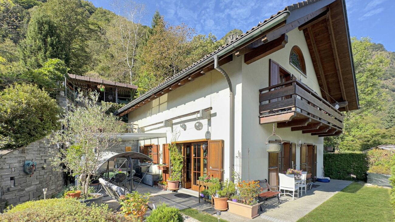 Außenansicht eines alpinen Wohnhauses mit Balkon und Garten
