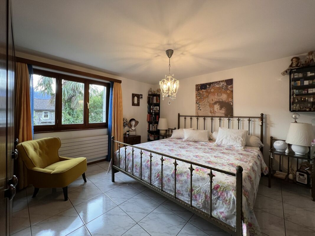 Schlafzimmer mit Metallbett und Fensterblick
