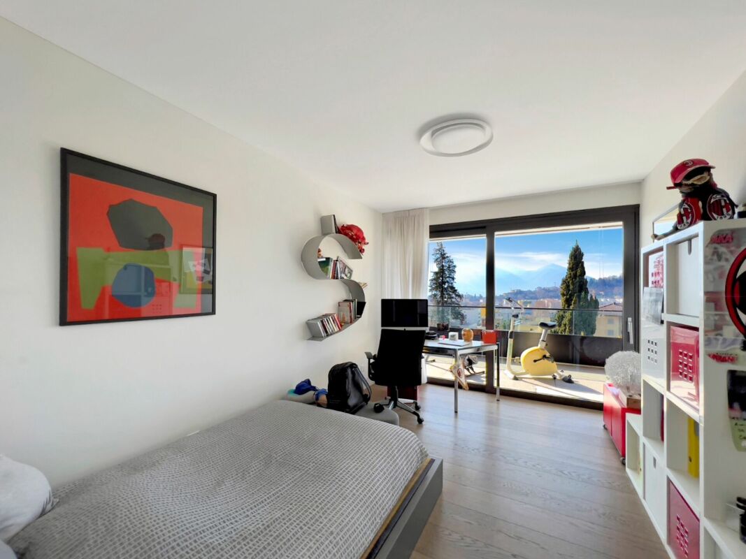 Helles Schlafzimmer mit Arbeitsplatz und Balkonblick