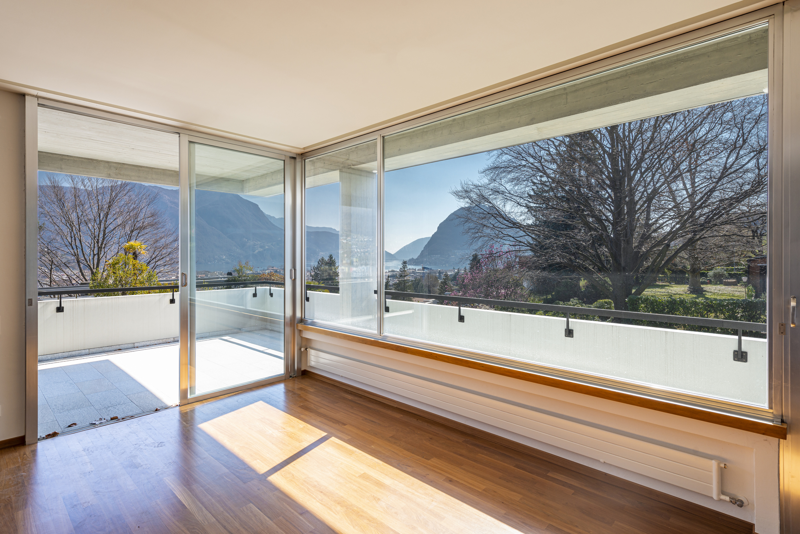 Helles Zimmer mit Panoramafenstern und Balkonblick