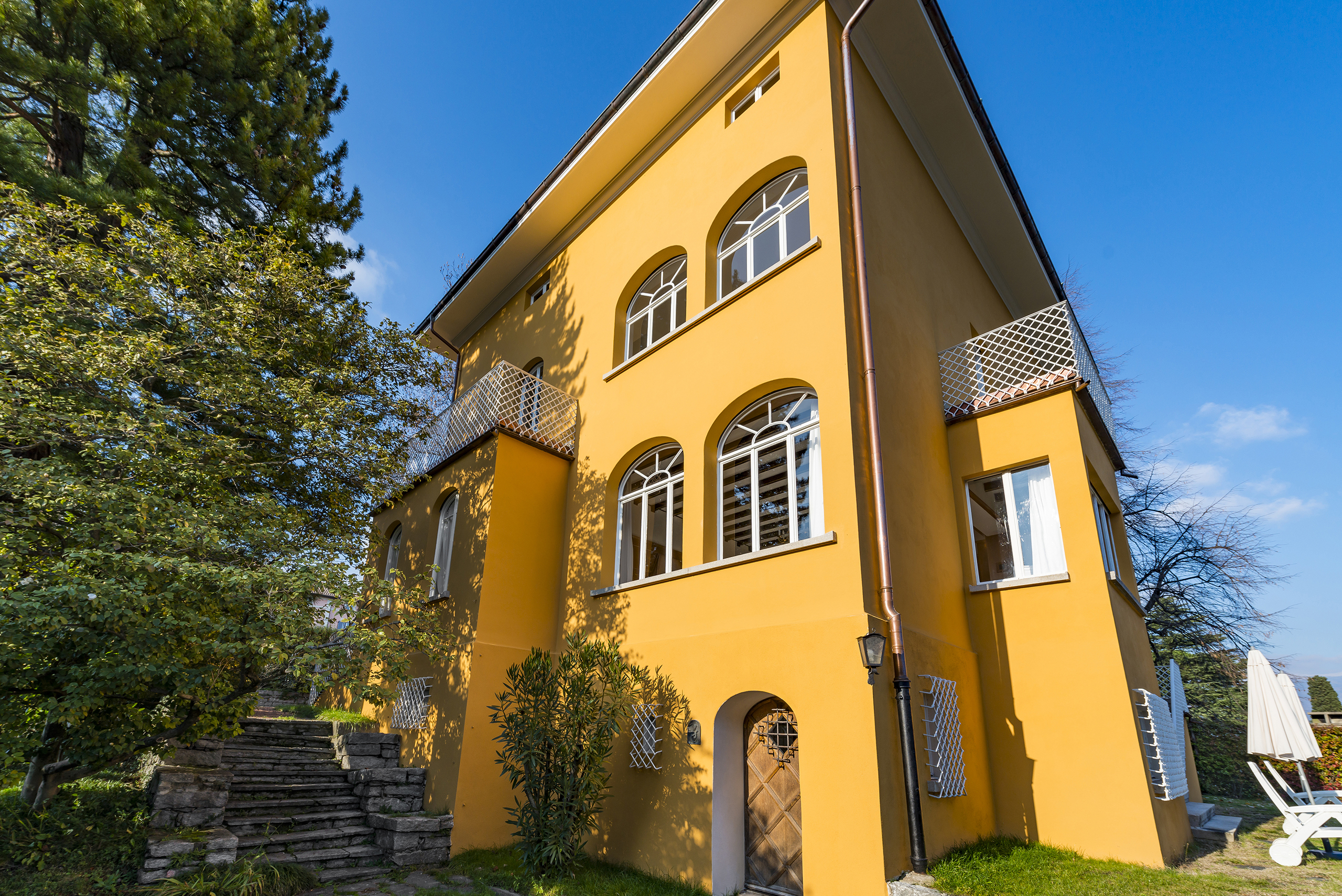 Gelbes Mehrfamilienhaus mit ar­chit­ek­to­ni­schen Rundbogenfenstern