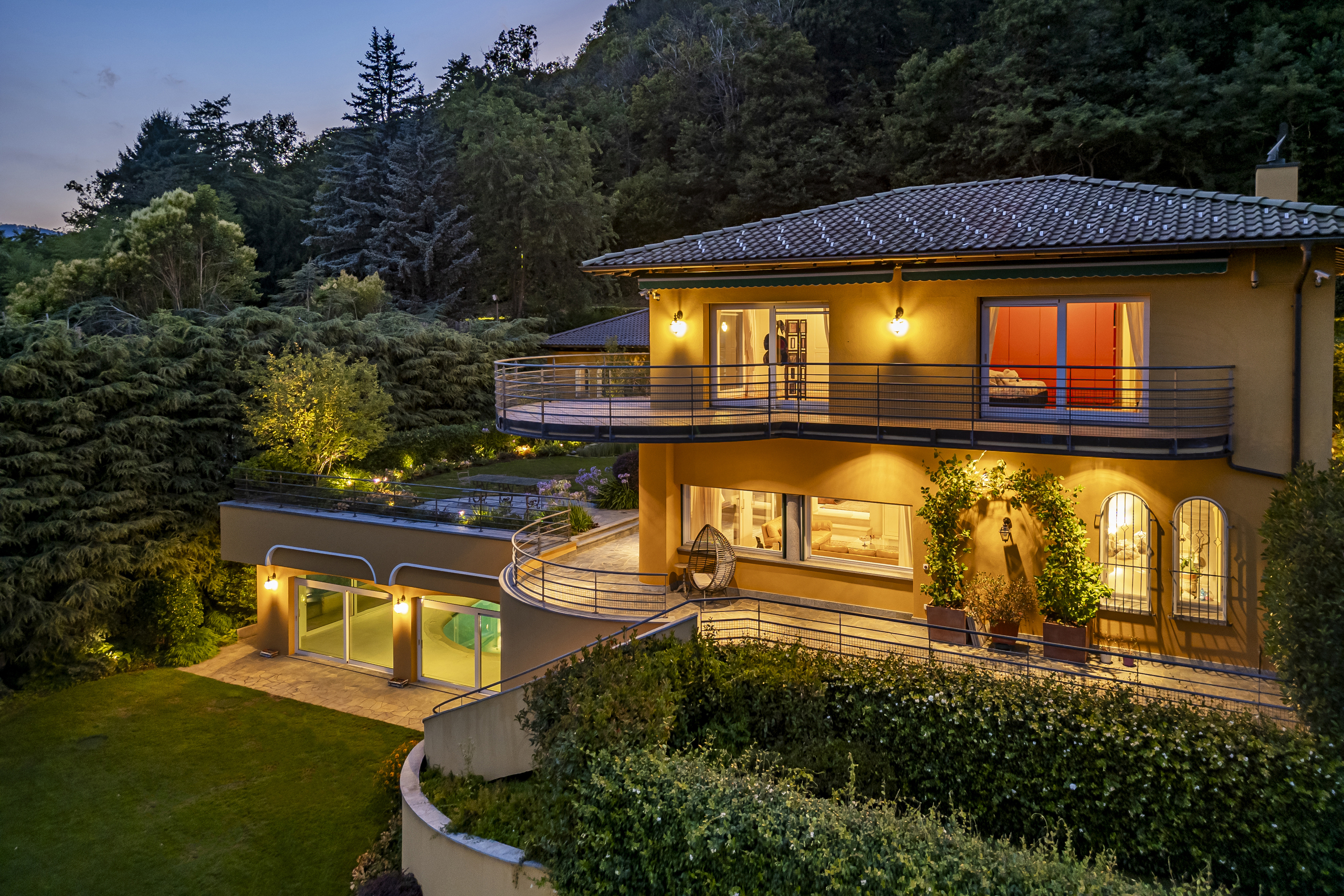 Beleuchtete Villa mit Garten bei Dämmerung