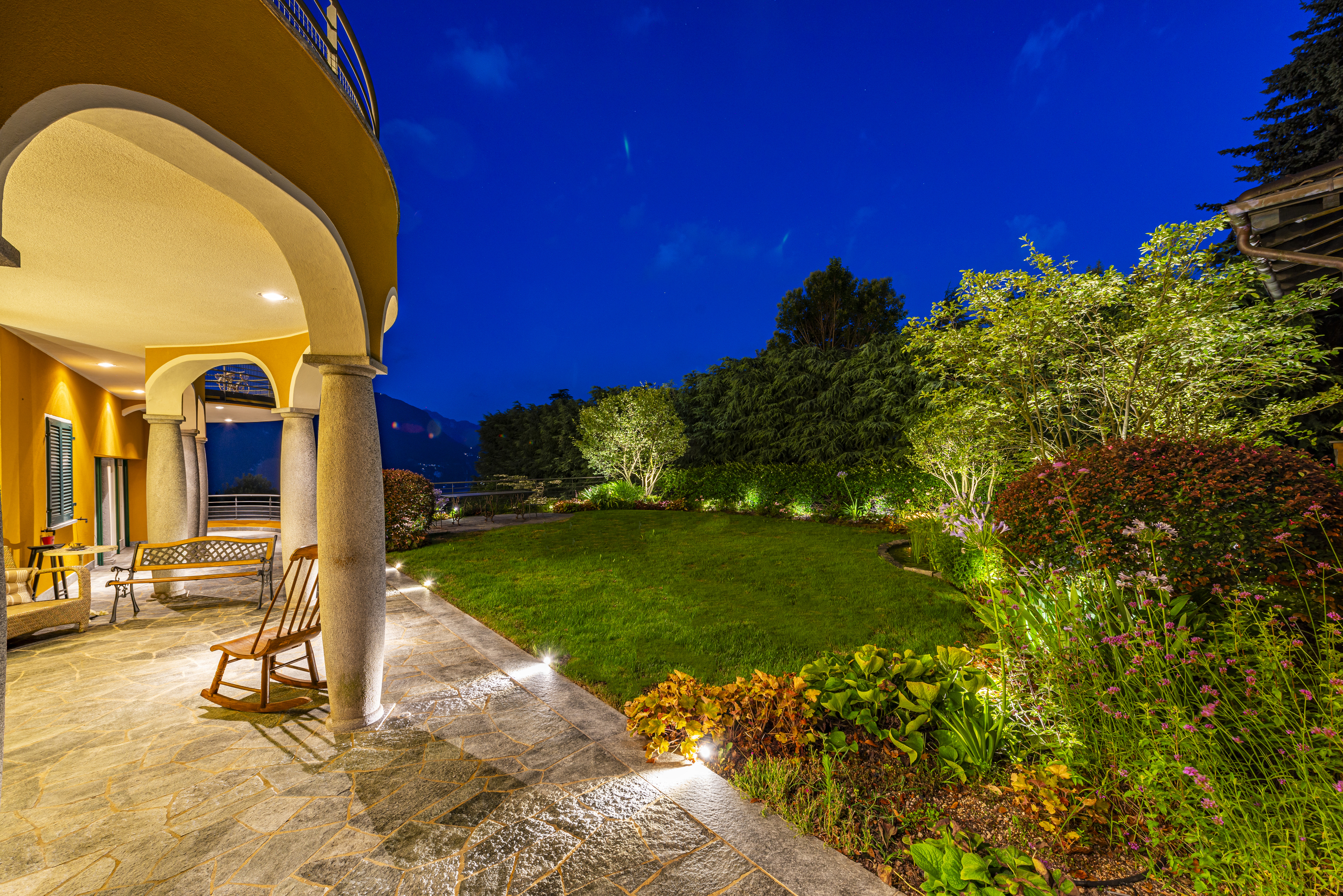 Überdachte Terrasse mit Garten bei Nacht